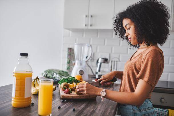 woman cutting fruit in a kitchen